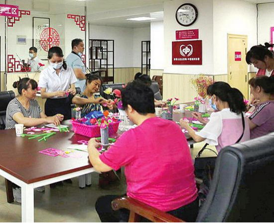 (图3养老服务中心的老人们在工作人员引导下制作手工花束。)