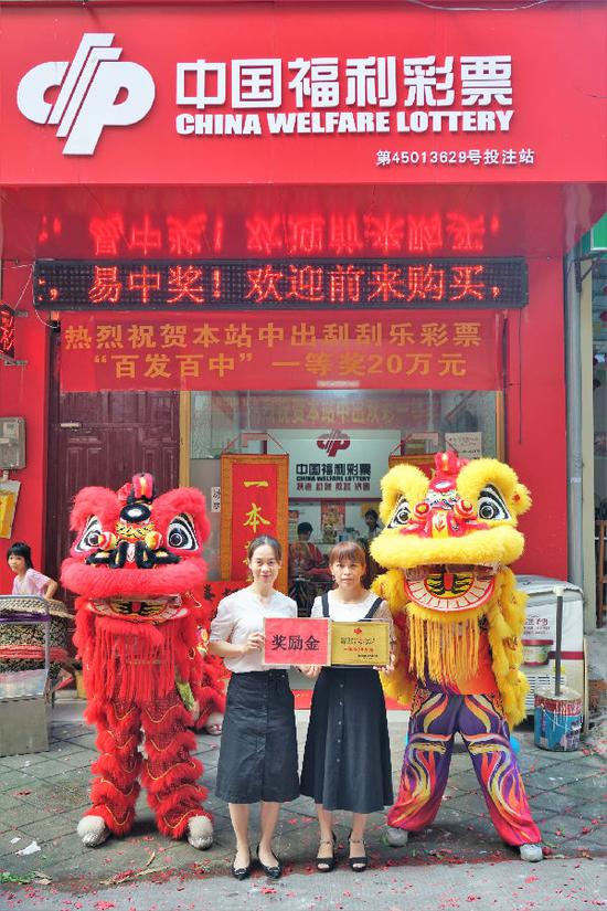 图为:南宁福彩工作人员为中奖的投注站业主(右)颁发牌匾和奖励金