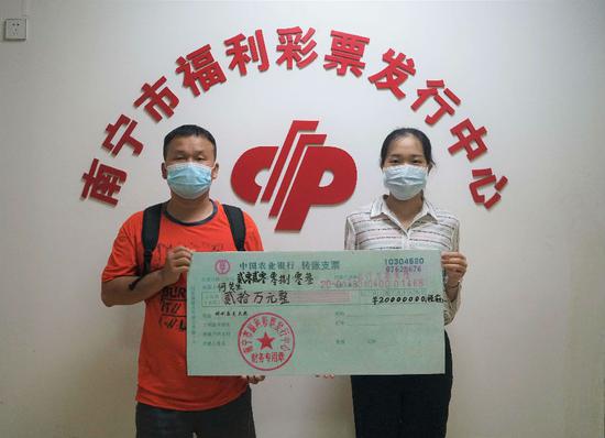 图为:市福彩中心工作人员为何先生(左)颁奖