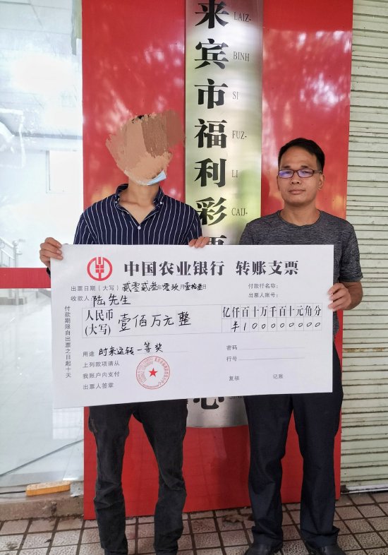 图为来宾市福彩中心工作人员向陆先生(左一)颁发奖金转账支票
