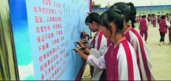 贵安新区民族中学学生在禁毒专题活动签名墙上签名。