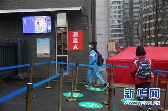 3月16日,学生在进入学校时通过体温监测点。新华网 卢志佳 摄