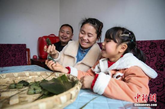 图为2月4日,贵州黔西化屋村村民赵玉学(左一)一家在制作黔西名小吃“黄粑”。 中新社记者 瞿宏伦 摄