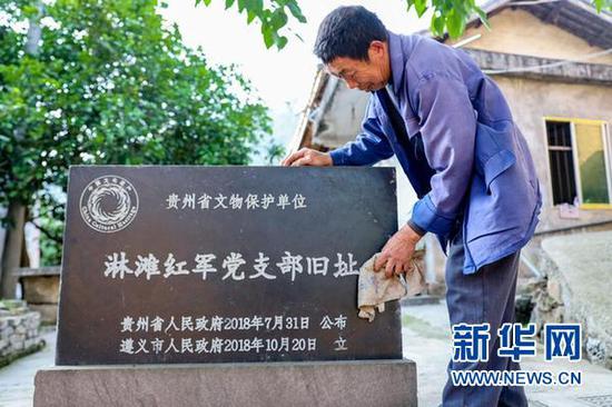 宋光平在擦拭家门前的“淋摊红军党支部旧址”石碑。(新华社记者欧东衢2021年4月21日摄)