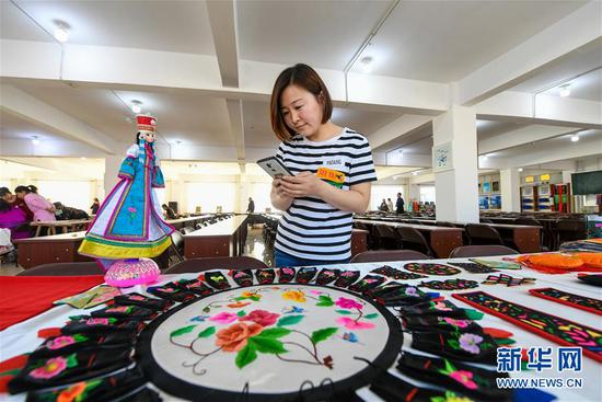 在内蒙古兴安盟科尔沁右翼中旗刺绣扶贫车间内的工艺品展示区,前来参观的游客在拍摄展品(2019年4月18日摄)。新华社记者 彭源 摄