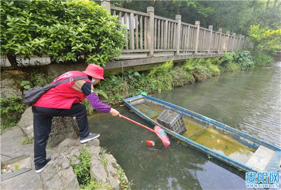黔灵山公园内,保洁阿姨清洁湖水中的垃圾