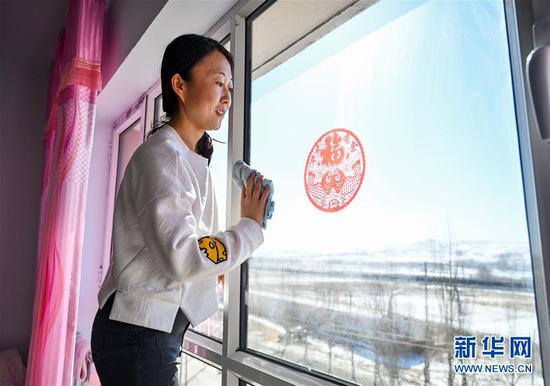 在内蒙古乌兰察布市卓资县易地搬迁房福安小区,今年在读大四的王清在擦窗户(2020年3月27日摄)。新华社记者 连振 摄
