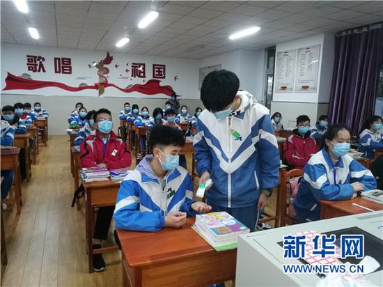 3月16日,贵阳市第二实验中学的初三学生在教室内测量体温。新华网发