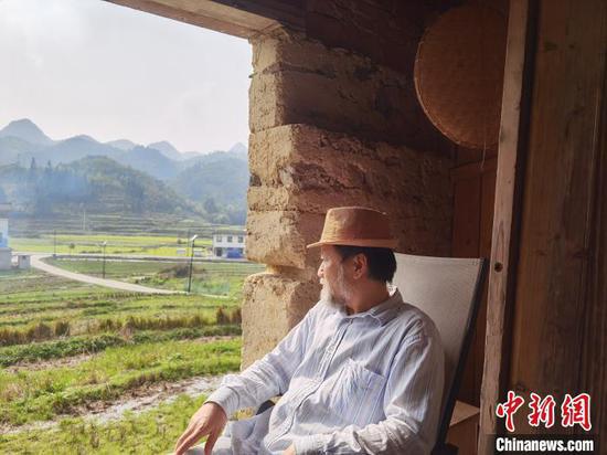 艺术家嵩田坐在“认养”的老屋看外面的风景。 周燕玲 摄