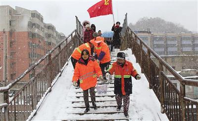 12月29日,钟山区红岩社区东风西路居委职工和辖区志愿者,在六盘水机务段人行天桥上撒盐除冰,确保过往行人安全。杨贵明 本报记者 翟汉元 摄