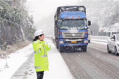 图为在遵赤高速19公里路段,民警王靖正在大雪中指挥车辆有序安全通行。