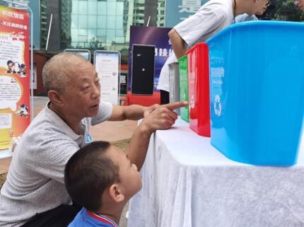 在活动现场,一位家长自发带着小朋友参观学习垃圾分类。记者 李凡 摄