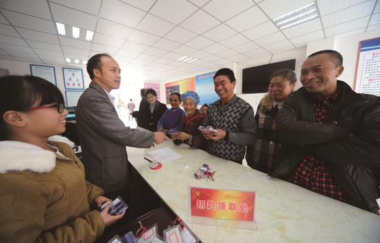 罗应和(左二)为易地扶贫搬迁群众发放新房钥匙