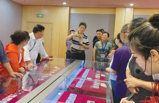 李连昌(中)在展览现场为观展市民讲解古币。
