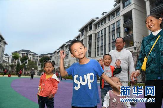 在贵州省遵义市正安县瑞濠街道搬迁安置点,搬迁户和孩子们在新居前留影(2019年10月10日摄)。新华社记者 杨文斌 摄
