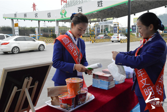 贵阳北收费站常白班班长张贤(左)与同事一起整理便民服务点