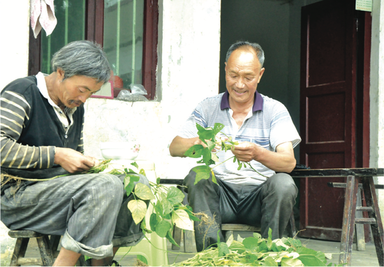 赵起友与他收养的赵周胜一起剥青豆( 熊军万 摄)