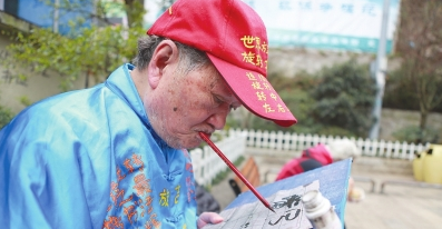 郑宽勤老人的嘴写书法绝活。