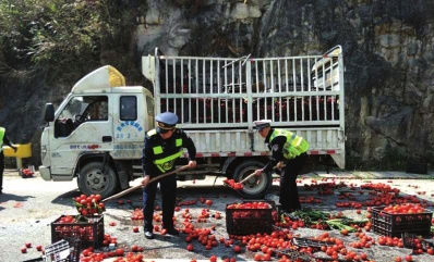 路政人员正在清理洒落在路面上的蔬菜。