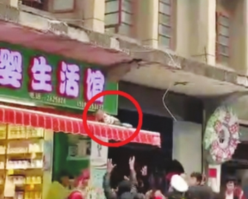 小男孩跌落到雨棚后,周边群众举手欲接住他。