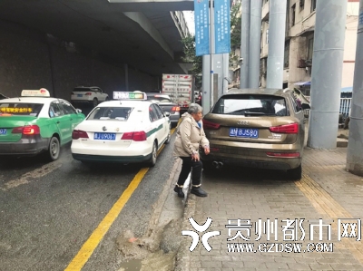 由于车辆占道,行人只能从马路上绕行。