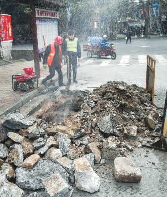挖开地面找到漏水点,工作人员准备修复