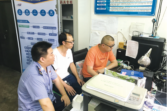 辖区居民刘作才(中)在居委会和市场监管部门的协助下完成工商营业执照年审