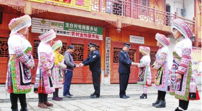 李德强(右边着警服者)与民警向苗乡群众发放警民联系卡。