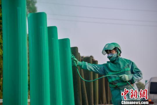 图为养护工人在东线高速上喷涂防眩板。洪坚鹏　摄