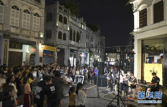 6月8日，游客在海口骑楼老街欣赏音乐表演。 新华社记者 杨冠宇 摄