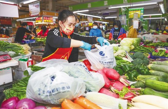 12月27日，在海口市五源河农贸市场，蔬菜摊主使用全生物降解购物袋