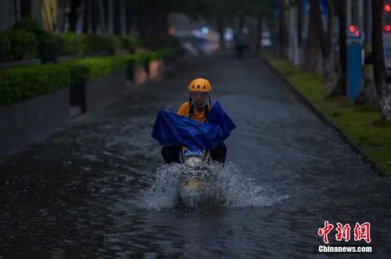 台风“森拉克”擦过海南三亚,琼岛出现强降雨天气。图为暴雨导致海口部分路段出现积水,外卖小哥冒险通过积水路段。骆云飞 摄