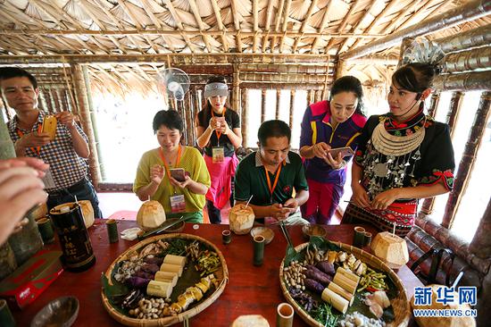 在海南省陵水黎族自治县，游客品尝黎族特色美食。新华网发（陈思国 摄）