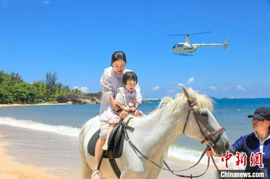 图为在天涯海角游览区，家长带着孩子在海边骑马。　游建行 摄