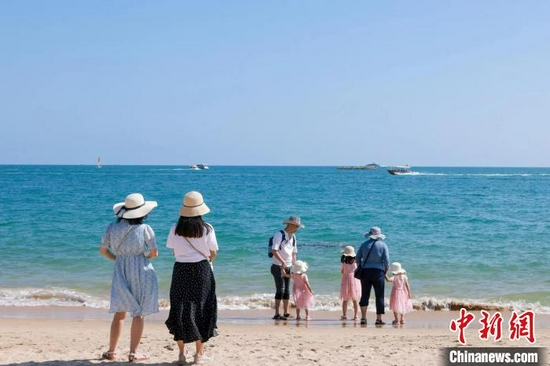 图为在天涯海角游览区，家长带着孩子在海边嬉浪。　游建行 摄