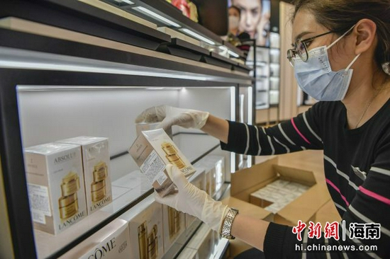 图为CDF海口日月广场免税店的工作人员将贴有溯源码的免税商品摆上货架。骆云飞摄