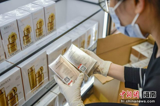 图为CDF海口日月广场免税店的工作人员将贴有溯源码的免税商品摆上货架。骆云飞摄