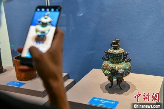 5月18日，“天涯觅珍——海南省博物馆征集成果展”在海南省博物馆开展。一名游客用手机拍摄展品。　骆云飞 摄