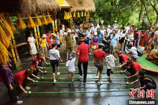 图为在亚龙湾热带天堂森林公园，家长带着孩子齐跳竹竿舞。　黄庆优 摄