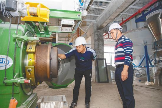 　　2月13日，在屯昌天之虹饲料加工厂项目的生产车间内，工作人员查看制粒机运行情况。本报记者 李天平 摄