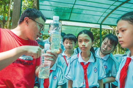 6月14日，在屯昌县新兴镇，当地疾控中心工作人员为孩子们讲解蚊子幼虫的产生和消灭方法。