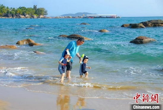 图为在天涯海角游览区，家长带着孩子在海边嬉浪。　游建行 摄
