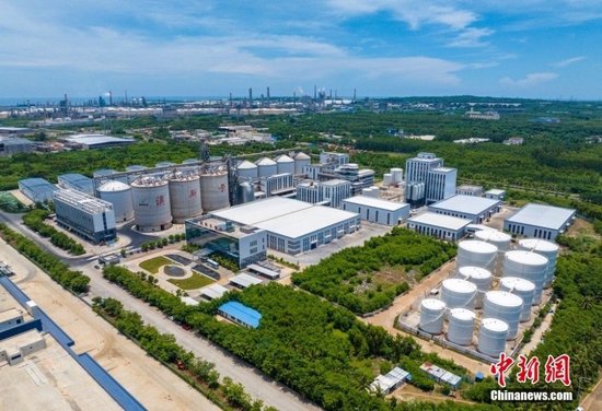  6月27日，“高质量发展调研行”海南主题采访活动来到海南洋浦保税港区，走进海南澳斯卡国际粮油有限公司的生产车间，自动生产线高速运转，大豆、菜籽等原料经过现代化设备加工后，变成了一瓶瓶食用油，最终被送到消费者手中。这是《海南自由贸易港建设总体方案》发布后，洋浦保税港区引进的首家大型实体企业，也是首个建成投产的生产性项目。图为位于洋浦保税港区的海南澳斯卡国际粮油有限公司。(无人机照片)中新社记者 骆云飞 摄