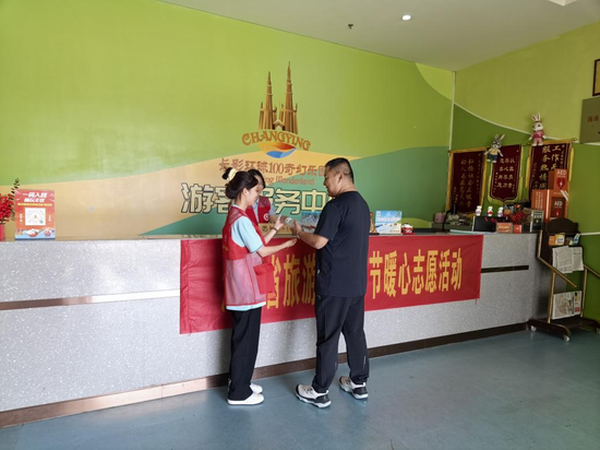 海南长影奇幻乐园志愿者为游客发放矿泉水。