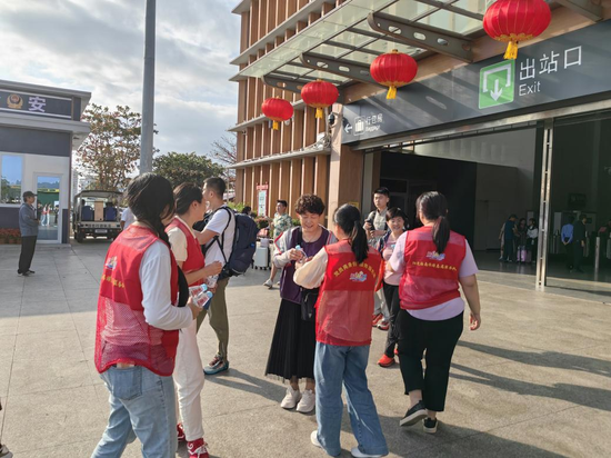 志愿者在三亚动车站为游客发放矿泉水。