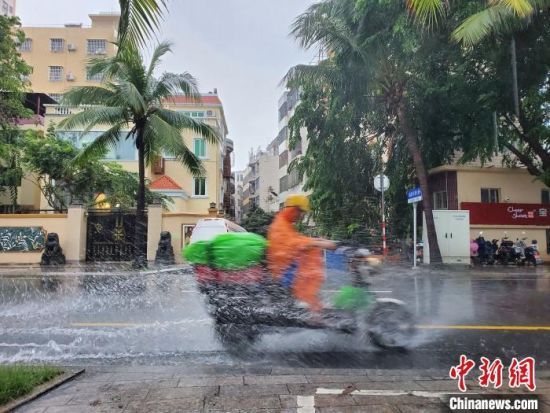 三亚市区，一辆电动车走过路面积水处。　记者王晓斌　摄