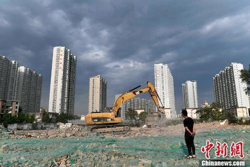 资料图：工人操作挖掘机在太原一商品房建设工地施工作业。中新社记者 韦亮 摄