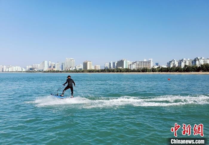 三亚湾，踩着动力冲浪板的人在海面滑过。　王晓斌 摄