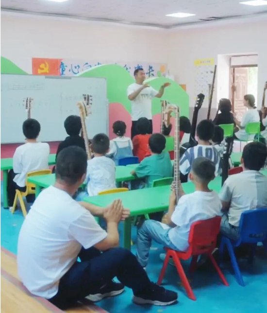孩子们在村委会的爱心小课堂学弹都塔尔琴