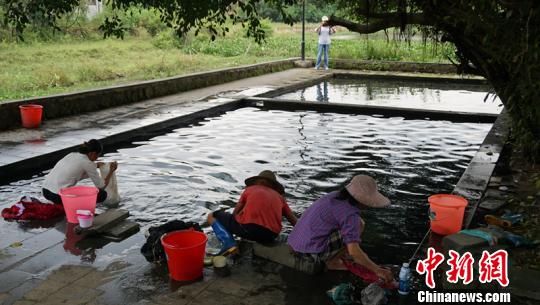 几名妇女在“雅蔡冷泉”旁一边聊天一边洗着衣物。　符宇群 摄